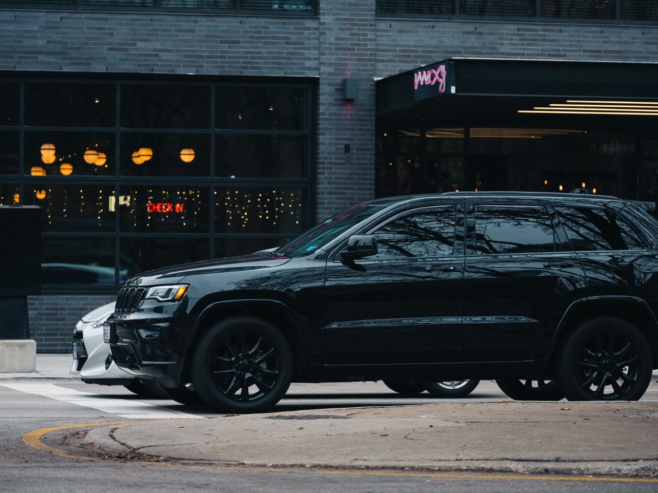 discover A sleek black SUV parked on a city street with modern buildings and outdoor lighting.