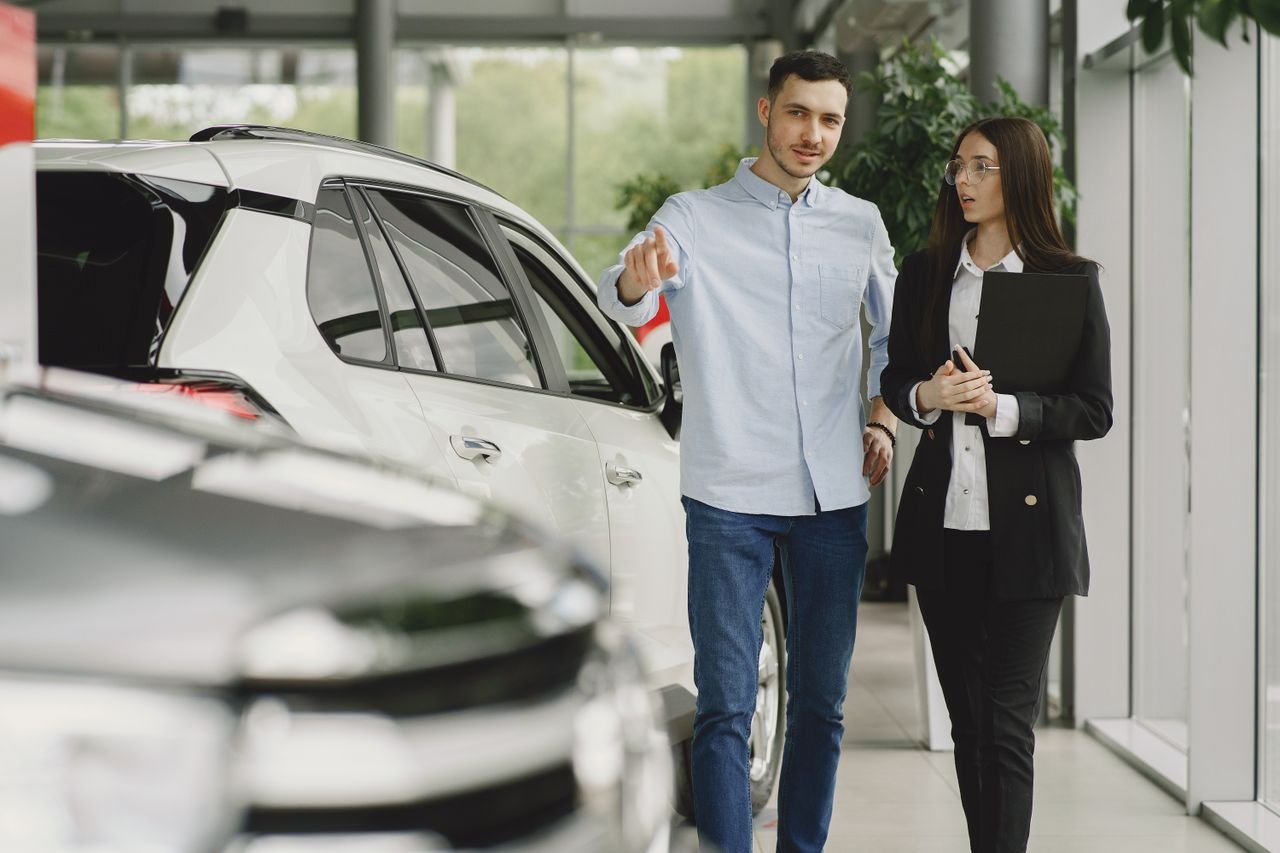 our-story Customer and salesperson discussing a vehicle inside a modern car dealership showroom.